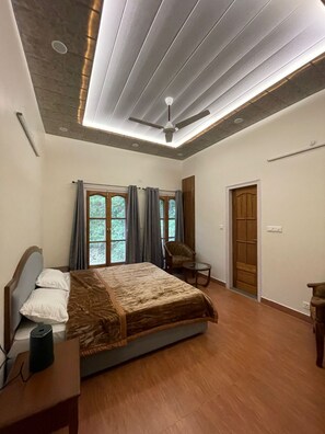 A bedroom with a bed, a chair, a table, and a door.