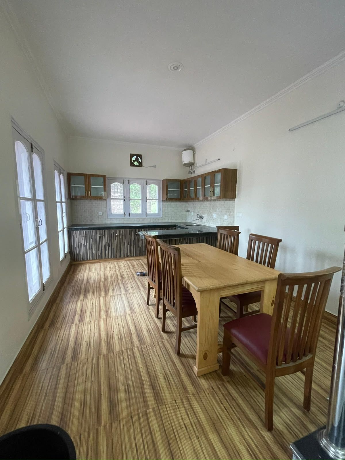 A spacious kitchen with a central island, wooden cabinets, and a dining area with chairs.