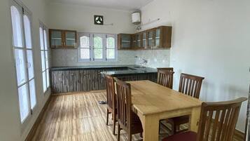 A spacious kitchen with a central island, wooden cabinets, and a dining area with chairs.