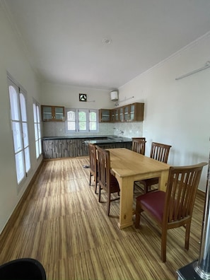 A spacious kitchen with a central island, wooden cabinets, and a dining area with chairs.