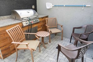 An outdoor kitchen area with a grill, chairs, and a table. - 4BR near Disney | Private pool, themed rooms (Kissimmee)