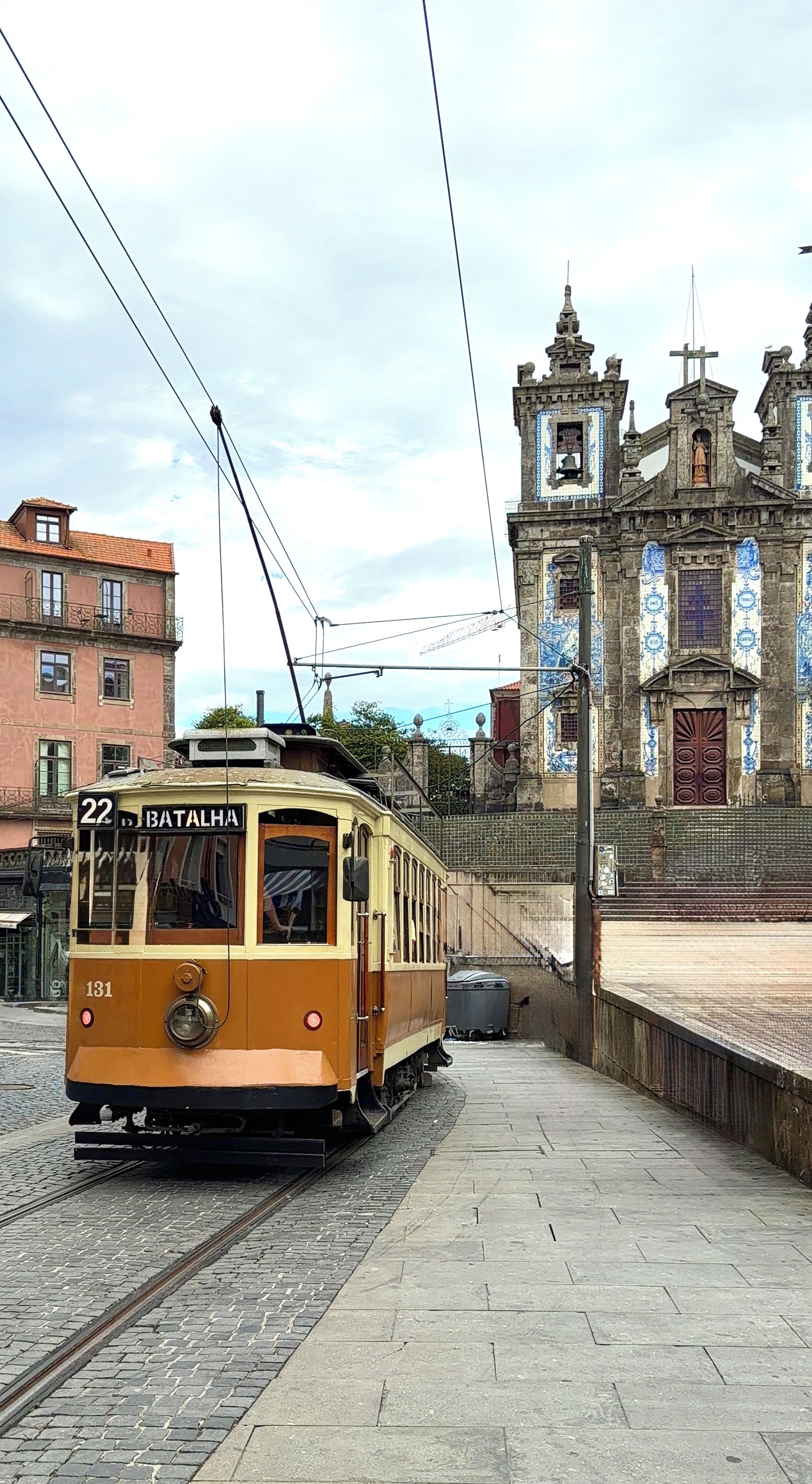 Eine historische Straßenbahn mit der Nummer 22 und dem Schriftzug 'BATALHA' an der Seite, geparkt auf Gleisen vor einem historischen Gebäude.