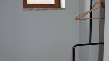 A room with a small table, a hanging clothes rack, and a window.