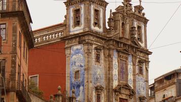 Um edifício histórico com intrincados trabalhos em azulejos azuis, uma torre de sino e uma fachada com o nome 'ABILINI'.