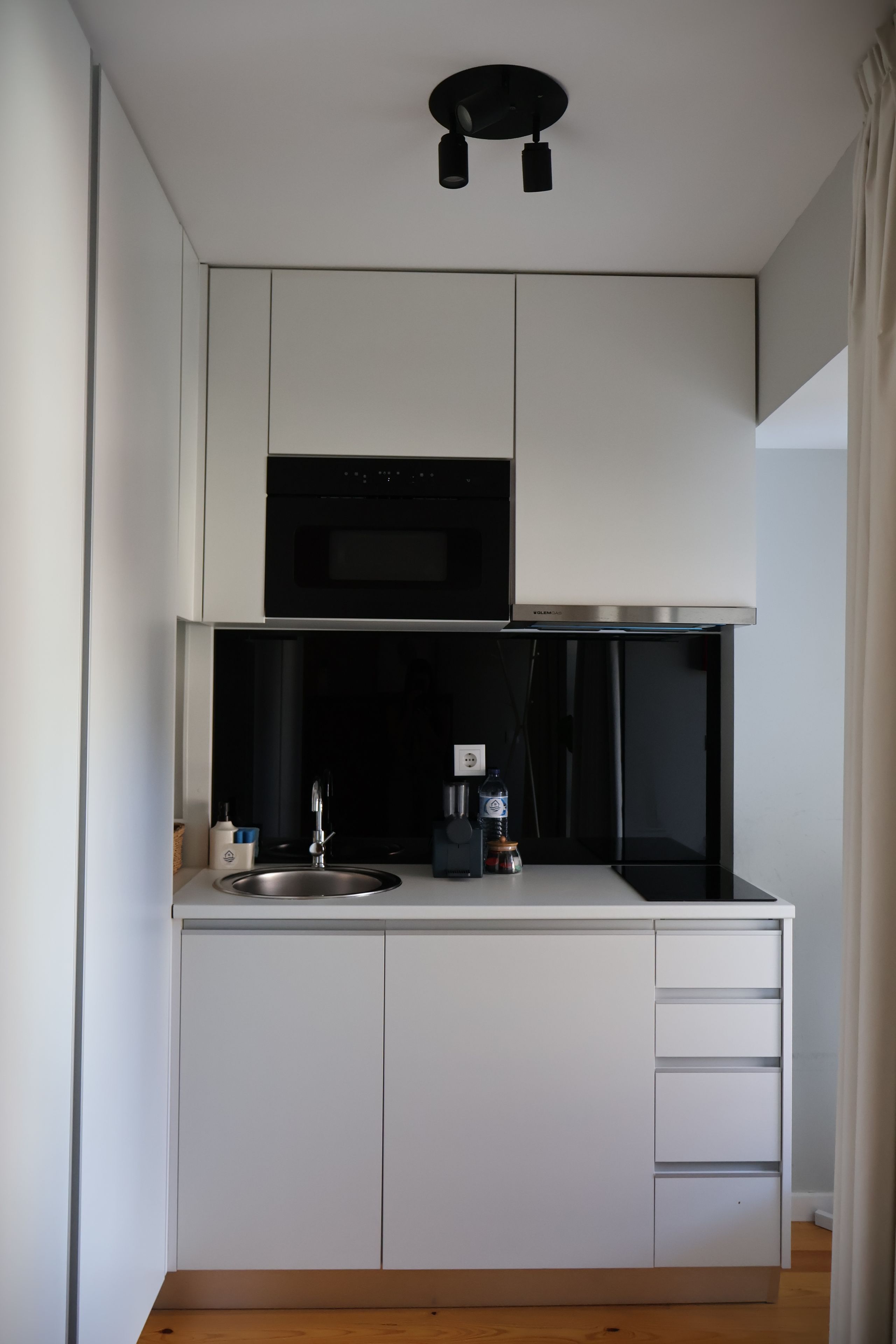 Una kitchenette funcional con microondas, pileta y placares.