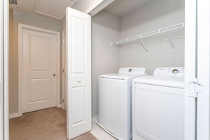 A laundry room with two white front-loading washing machines and a white door. - 4BR Le Reve townhome | Pool & themed rooms (Kissimmee)