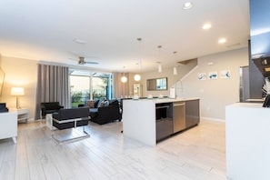 A modern living space with a kitchen, dining area, and seating area. - 4BR Le Reve townhome | Pool & themed rooms (Kissimmee)