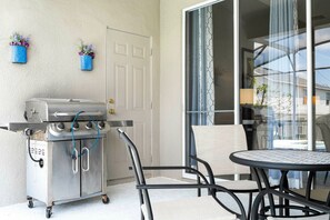 A patio area with a grill, a table, and chairs. - 4BR Windsor Palms | Pool, spa & Mickey room (Kissimmee)