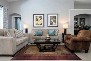 A living room with two sofas, a coffee table, and a patterned rug. - 4BR Windsor Palms | Pool, spa & Mickey room (Kissimmee)