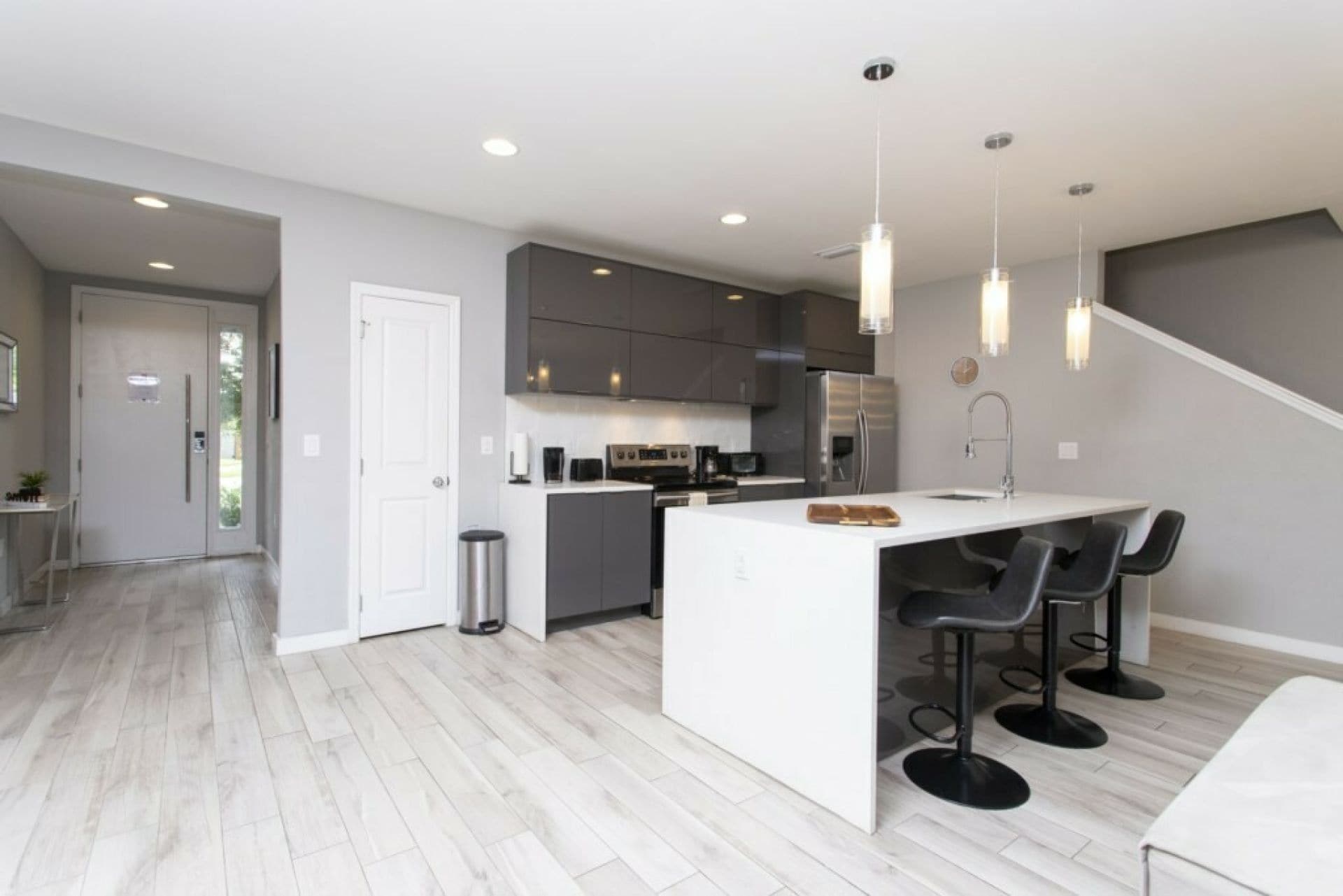 Une cuisine moderne dotée d’un îlot central, de tabourets de bar et d’un escalier menant à un autre niveau.
