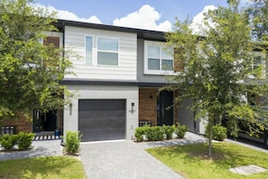 A modern two-story residential building with a garage, a driveway, and a well-maintained lawn. - 4BR Le Reve home | Pool & theme rooms (Kissimmee)