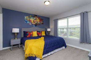 A bedroom with a bed, two bedside tables, a window with curtains, and a ceiling light. - 4BR Le Reve home | Pool & theme rooms (Kissimmee)