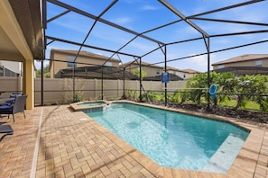 Piscina com deck de tijolos, cercada por uma grade de metal e placa com as regras da piscina.