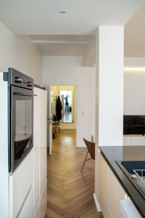 A modern kitchen with a built-in oven and a wooden floor. - Brussels South - Cosy Appartment (Anderlecht (Brussels))