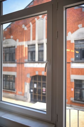 A window with a view of a building with a brick facade and multiple windows. - Brussels South - Cosy Appartment (Anderlecht (Brussels))
