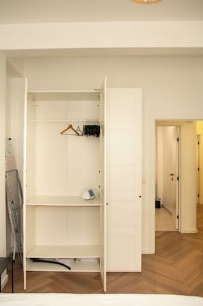 A walk-in closet with open doors, a hanging rack, and a shoe rack. - Brussels South - Cosy Appartment (Anderlecht (Brussels))