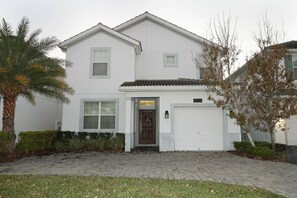 A two-story residential building with a front garage door, a small porch, and a mailbox. - Themed 5BR near Disney | Pool, game room (Kissimmee)