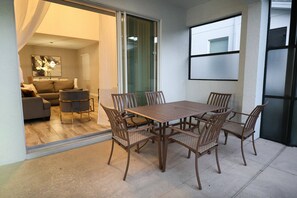 A dining area with a table and chairs, a sofa, and a sliding glass door leading to a living room. - Themed 5BR near Disney | Pool, game room (Kissimmee)