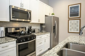 A modern kitchen with stainless steel appliances, white cabinetry, and granite countertops. - 5BR Harry Potter townhouse | 15 min to Disney (Kissimmee)
