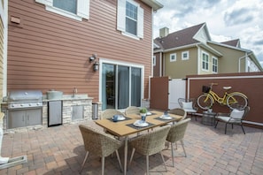 A patio with a table and chairs, a grill, and a bicycle. - 5BR Harry Potter townhouse | 15 min to Disney (Kissimmee)