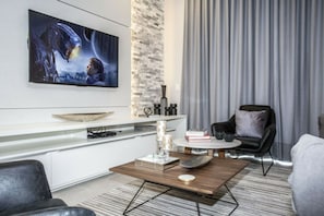 A modern living room with a flat-screen TV, a coffee table, a sofa, and a chair. - 5BR Harry Potter townhouse | 15 min to Disney (Kissimmee)