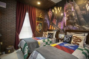 Ein Zimmer mit zwei Betten, einer Ziegelwand, einem Fenster mit Vorhängen und einem Wandgemälde eines Schlosses.