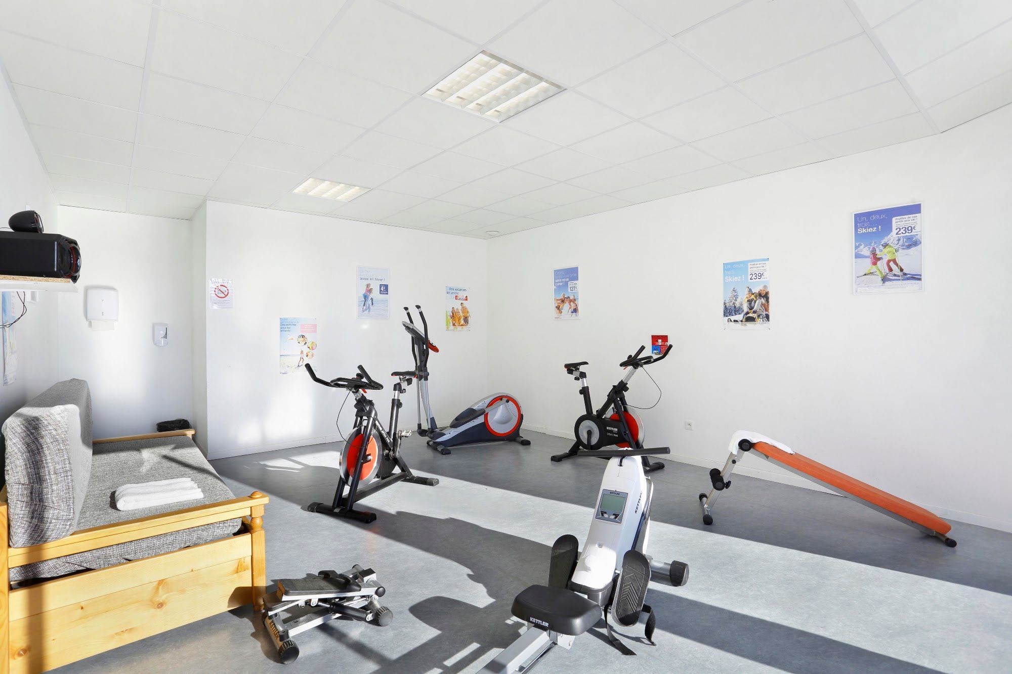 A gym with exercise equipment, a bench, and posters on the walls.