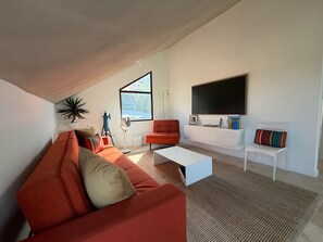 Ett modernt vardagsrum med en soffa, ett soffbord och en tv som är monterad på väggen.