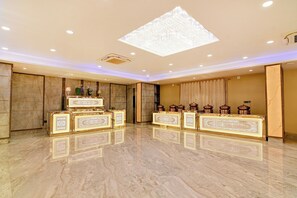 A spacious hotel lobby with marble flooring, a large chandelier, and ornate furniture.