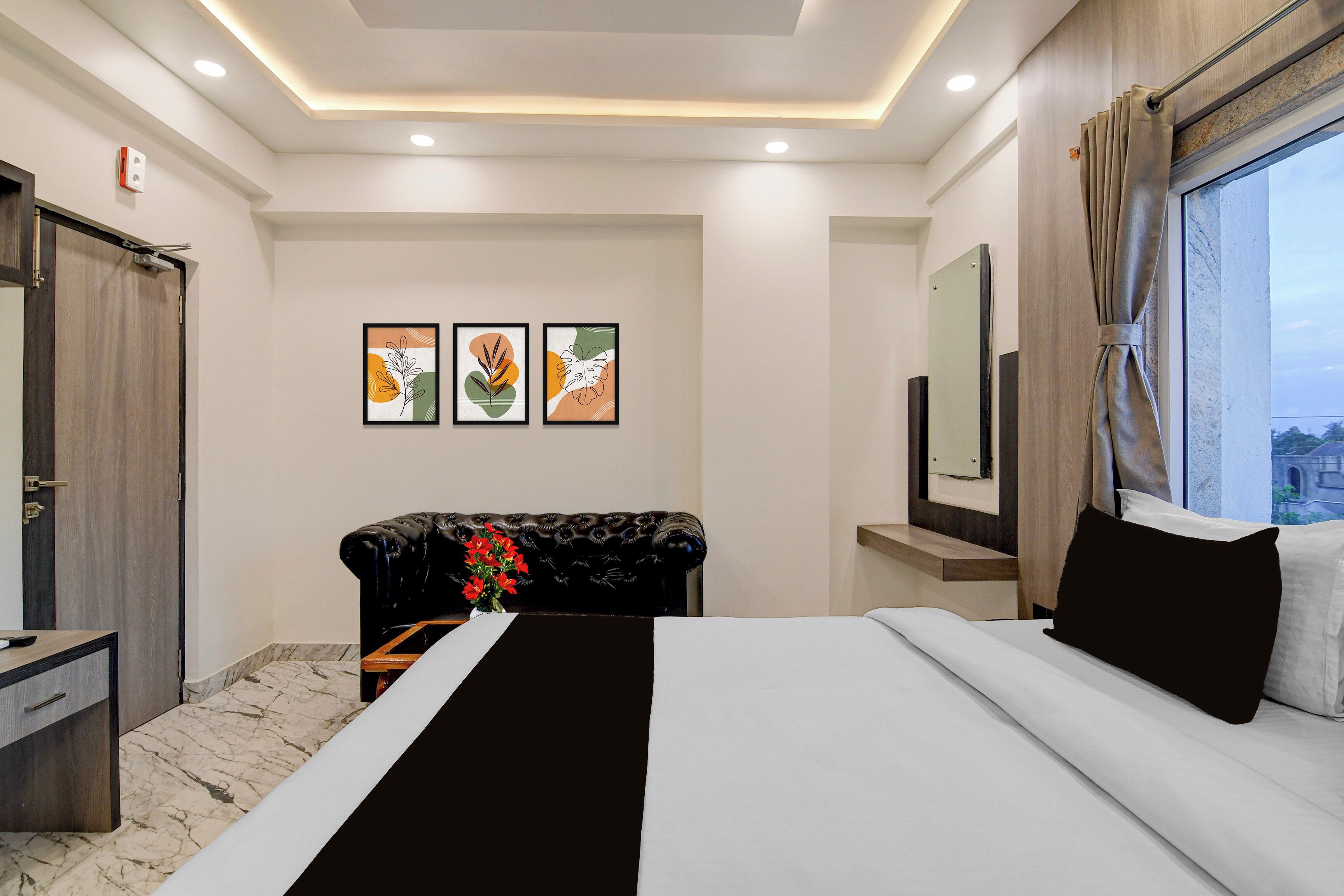 Una habitación de hotel con cama, escritorio, espejo y obras de arte en la pared.