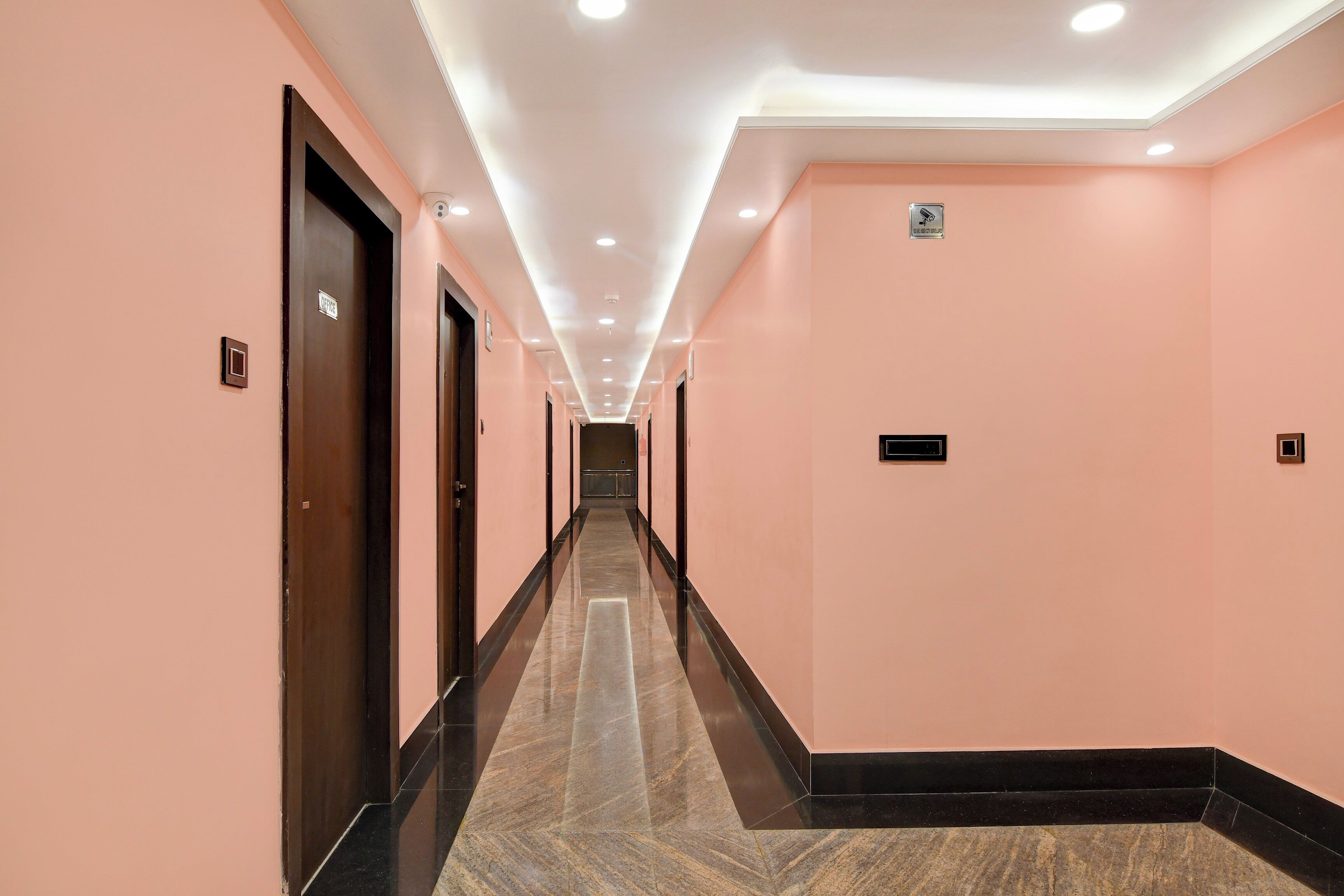 A corridor with doors on both sides, a sign indicating an office, and a tiled floor.