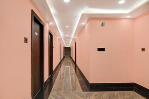 Un pasillo con puertas a ambos lados, un letrero que indica una oficina y un piso de baldosas.