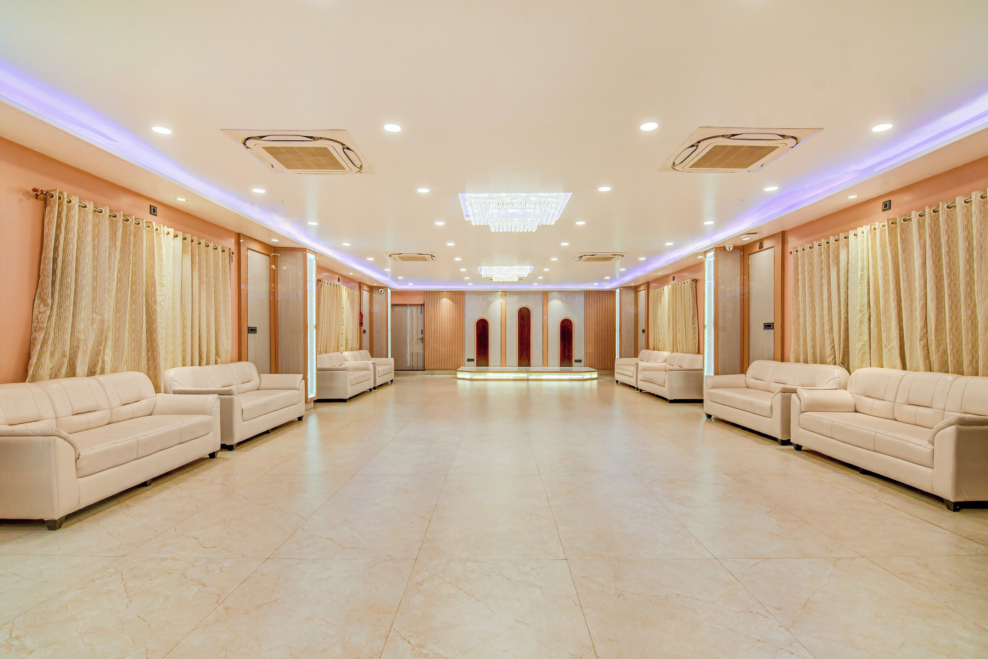A spacious room with a row of sofas facing a central area with a light fixture.
