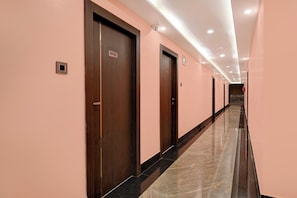 Un pasillo de hotel con puertas indicadas como 'OFFICE', un detector de incendios y un extintor.