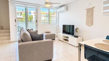 A modern living room with a sofa, TV, and dining table.