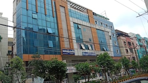 A multi-story building with a modern glass facade, a sign for a hotel, and a sign for luxury A/C rooms.
