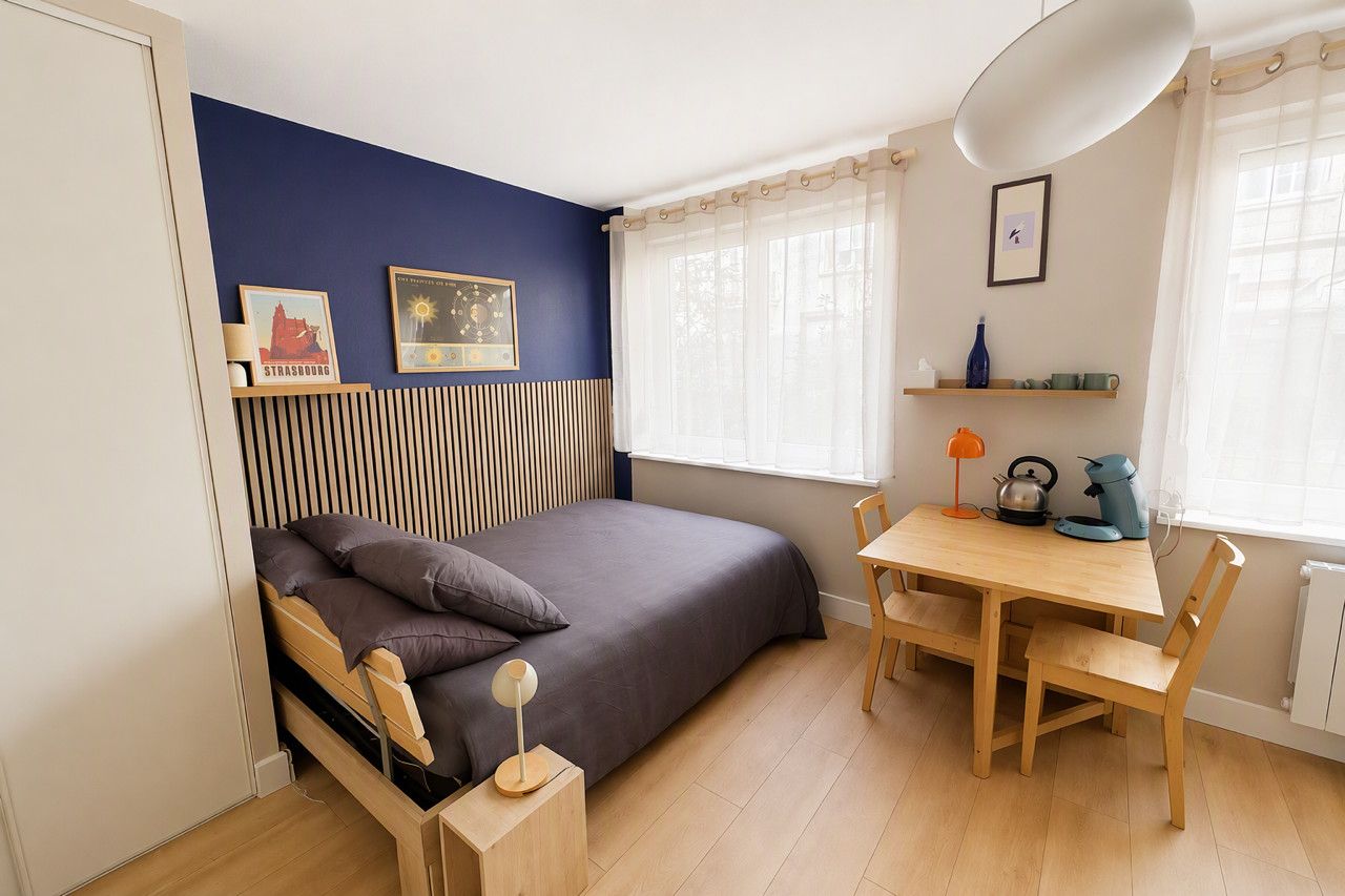 Een slaapkamer met een bed, nachtkastje, lamp en een raam met gordijnen.