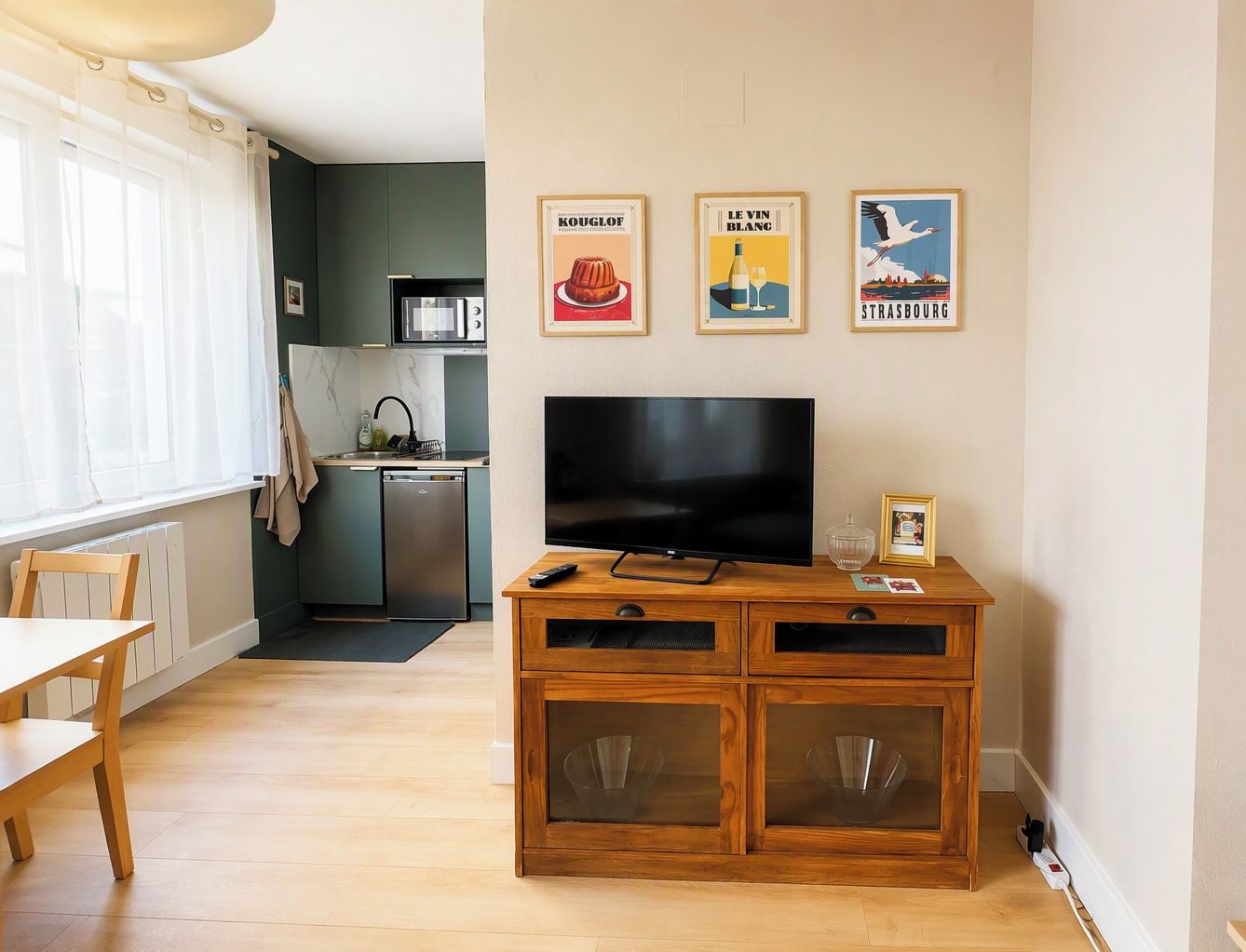 Un salon comprenant un meuble en bois, un téléviseur et un coin repas avec une table et des chaises.