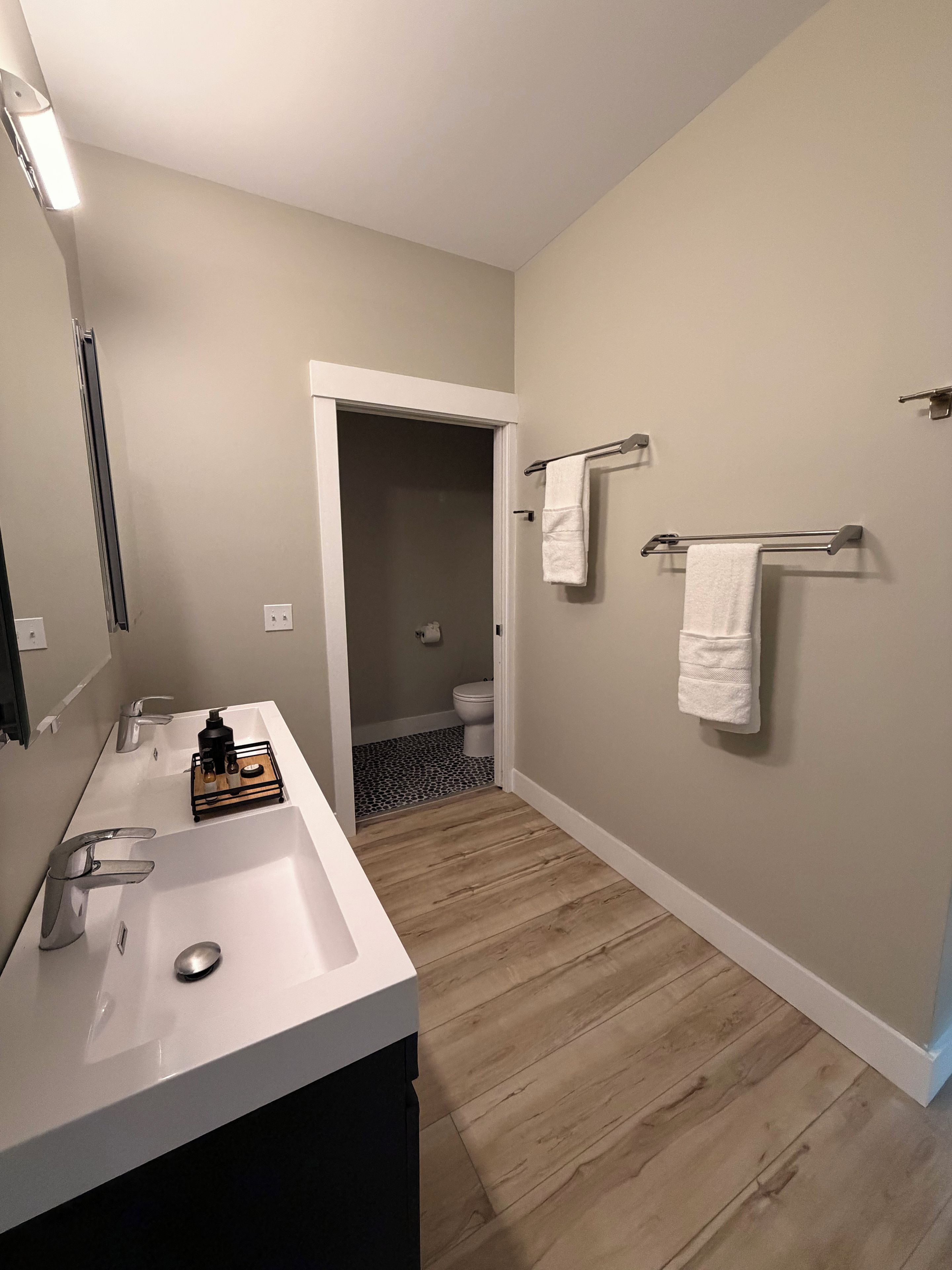 A bathroom with a white sink, two towel racks, and a mirror.