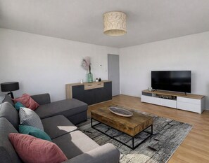 A modern living room with a sofa, coffee table, TV, and minimalist decor. - Bright apartment with terrace and cathedral view (Strasbourg)