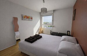 A bedroom with a bed, a window, a radiator, and a painting on the wall. - Bright apartment with terrace and cathedral view (Strasbourg)