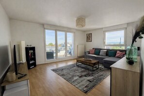 A modern living room with a sofa, coffee table, and a bookshelf. - Bright apartment with terrace and cathedral view (Strasbourg)