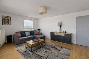 Un salon moderne avec un canapé gris, une table basse en bois et un meuble gris.