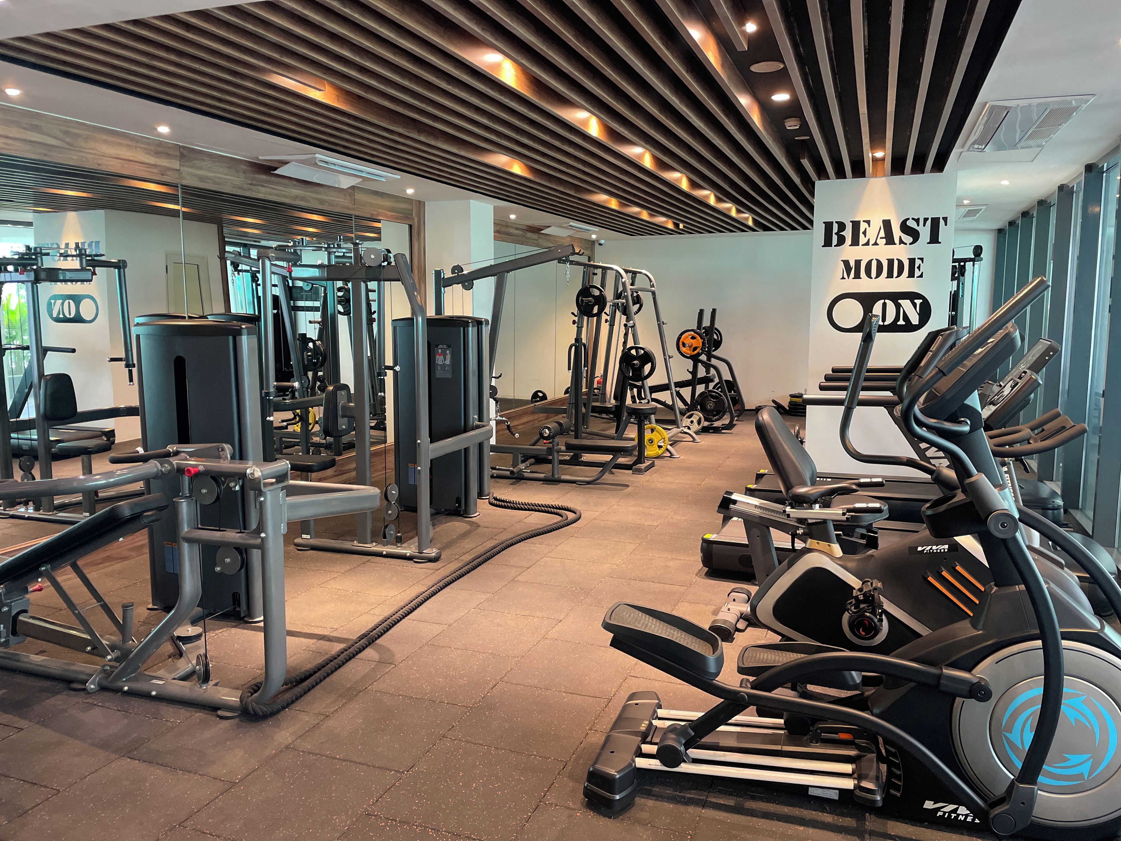 A gym with various exercise equipment, including treadmills and weight machines, and a sign that reads 'BEAST MODE'.