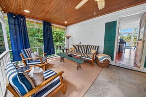 A covered outdoor seating area with a wooden ceiling, striped sofas, and a table with a lamp. - Corrotoman River Retreat - Dock, Kayaks, Shuffleboard & Views (Lancaster)