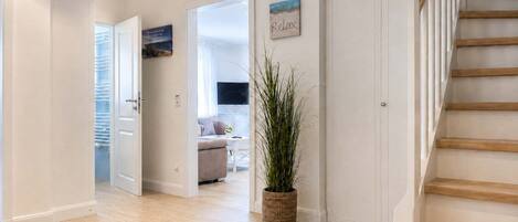 A hallway with a staircase, a potted plant, and a 'Relax' sign on the wall.