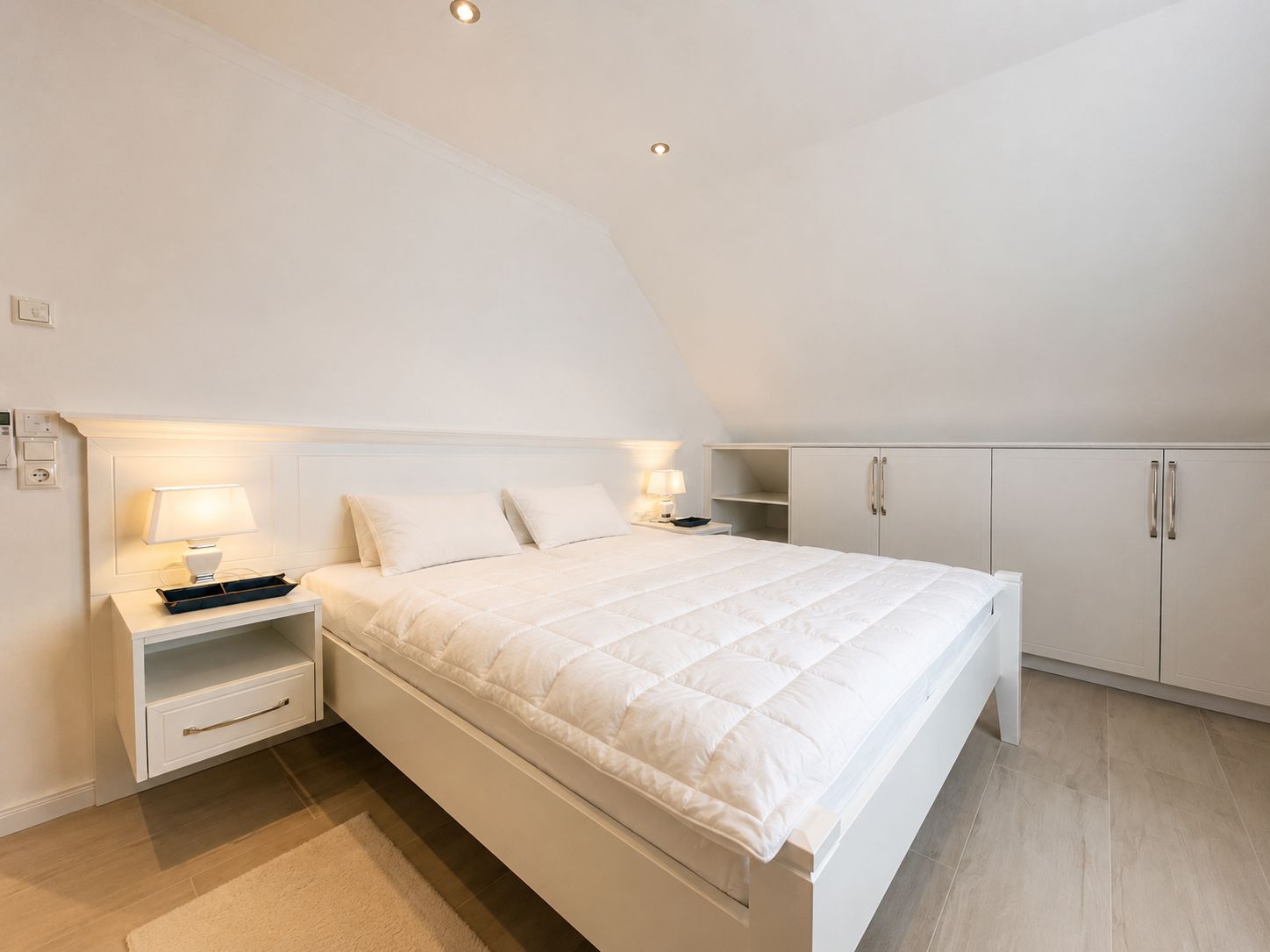 A bedroom with a bed, bedside tables, a wardrobe, and a ceiling light.