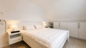 A bedroom with a bed, bedside tables, a wardrobe, and a ceiling light.