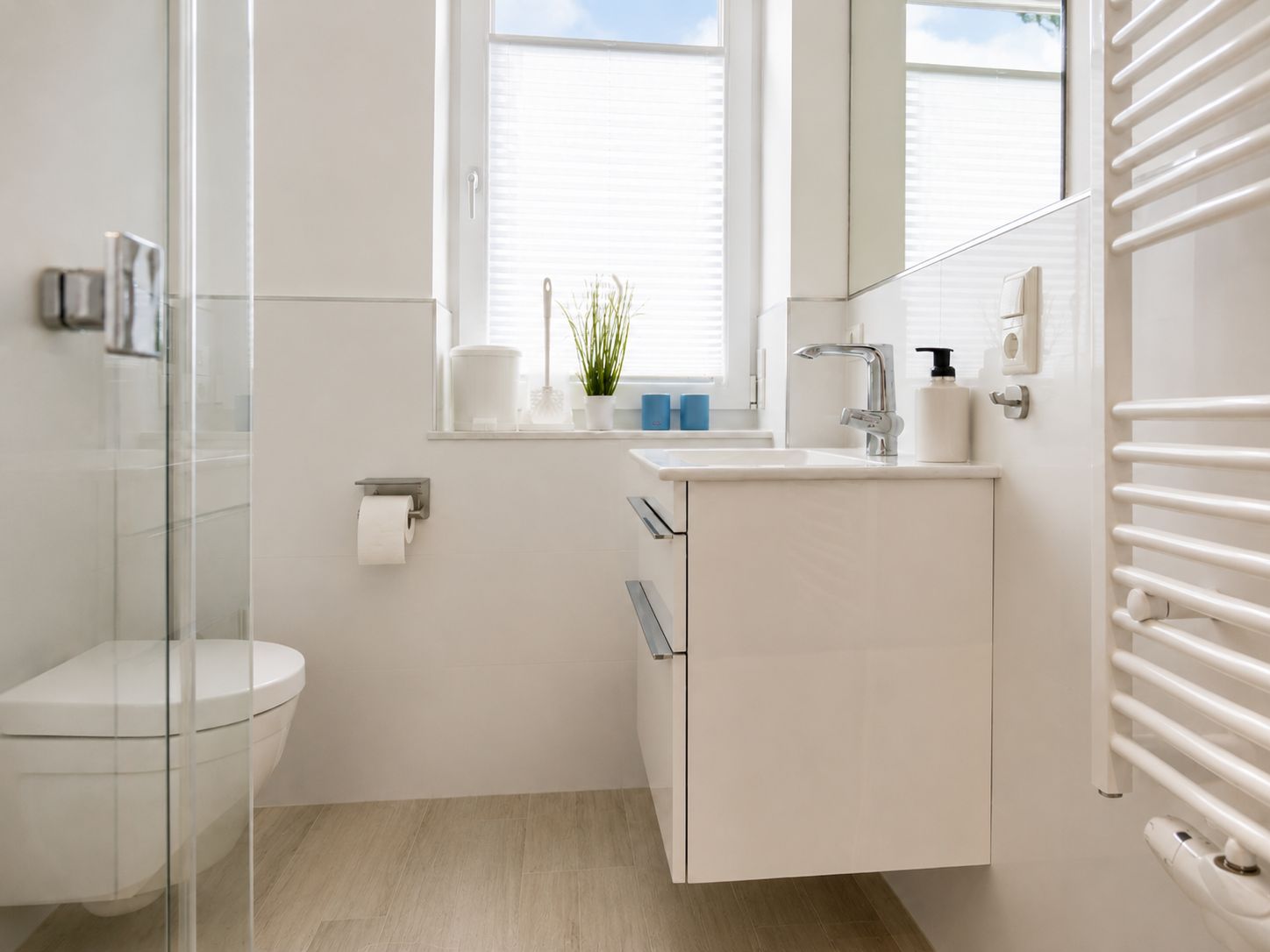 Ein modernes Badezimmer mit Duschkabine aus Glas, Toilette, Waschbecken mit Spiegel und Handtuchhalter.