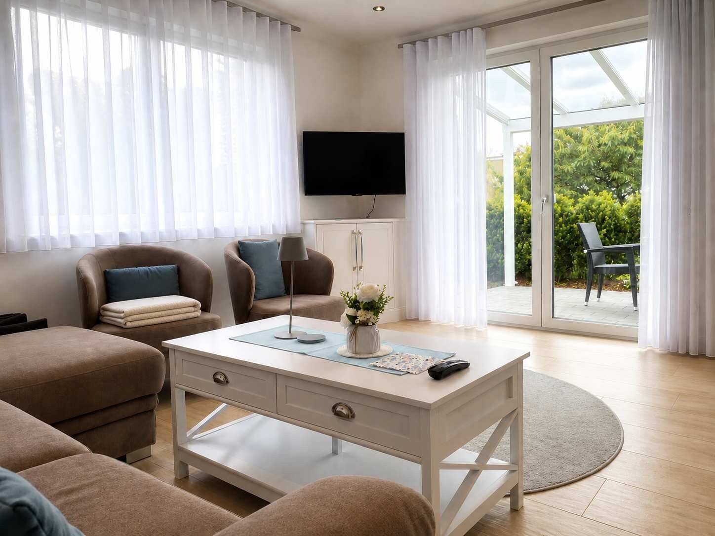 A modern living room with a sofa, a coffee table, a TV, and a sliding glass door leading to an outdoor area.